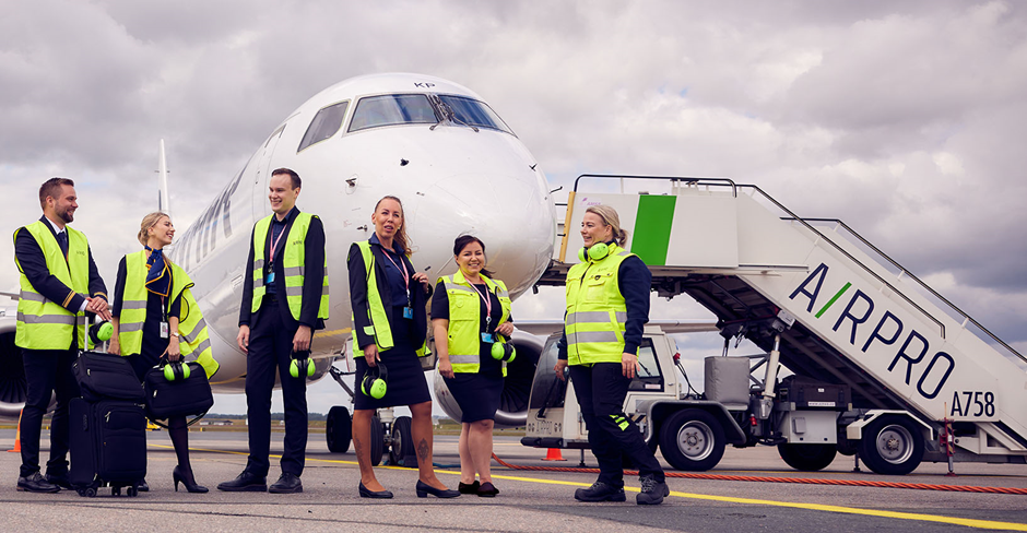 A group of people in safety vests standing in front of a plane 
Description automatically generated